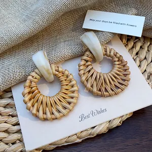 Detail of round rattan woven earrings with marble texture resin top on natural decor