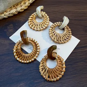 Detail of bohemian round rattan earrings in ivory and dark amber resin on a woven mat
