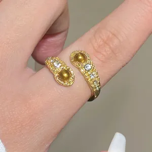 Detailed close-up of golden hammer-textured ring with brown stones and sparkling zircons