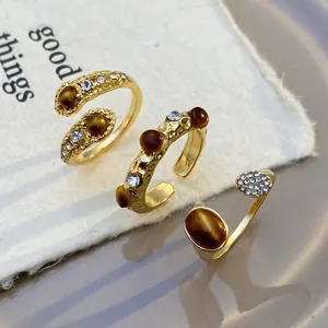 Three-piece set of golden open rings with tiger eye stones and diamonds in boho style