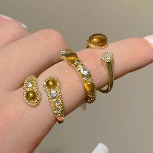 Vintage hammered gold rings with amber tiger eye stones and diamonds on fingers