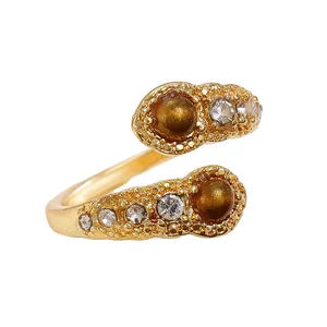 Golden bypass ring with tiger eye stones and clear zircons on white background