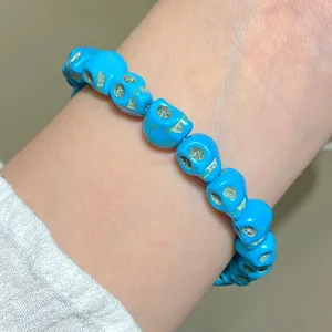 Gros plan du bracelet tête de mort punk avec texture turquoise bleue sur le poignet