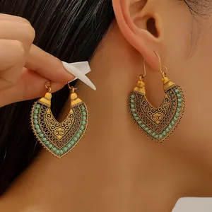 Bohemian gold hollow flower drop earrings featuring emerald green bead trim details
