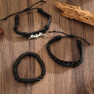 Set of three black punk bracelets featuring a silver bat pendant on rustic wood background