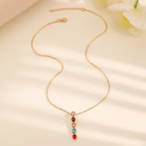 Detail van de gouden ketting met vijf kleurrijke druppelvormige edelstenen als hanger