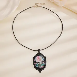Detailopname van ovale glazen hanger met roze roos en kanten metalen omlijsting