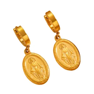 Gros plan détaillé des boucles d'oreilles créoles dorées avec pendentifs de la Vierge Marie
