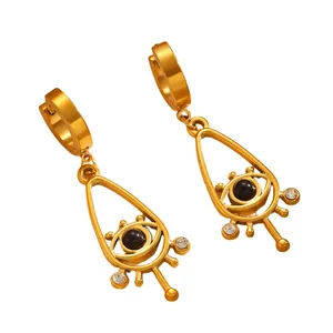 Détail de boucles d'oreilles créoles mauvais œil dorées avec perles noires et cristaux