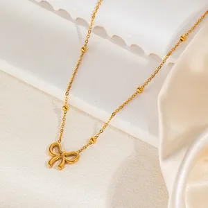 Detailed view of a gold bow pendant necklace with delicate beaded chain on silk