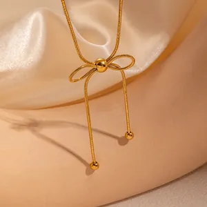 Vista macro della collana con ciondolo a fiocco dorato, catena snake e perle tonde