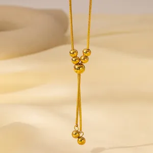 Detail of gold snake chain necklace featuring elegant bead tassels and polished metal finish