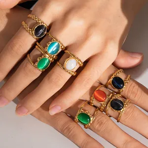 Close-up of vintage gold rings with colorful oval cat eye stones on multiple fingers