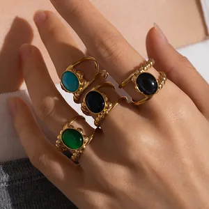 Detail of stacked vintage rings with colorful oval stones and beaded gold metal edges