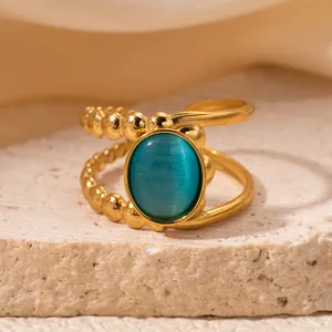 Asymmetric gold-plated open ring featuring a blue cat-eye stone and beaded texture