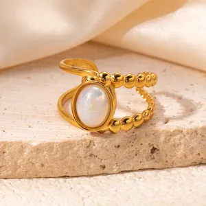 Detail of gold-plated asymmetric ring with opalescent stone on elegant silk fabric