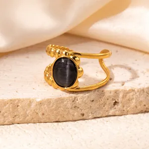 Detail of gold-plated asymmetric ring featuring oval grey cat's eye stone and beaded texture