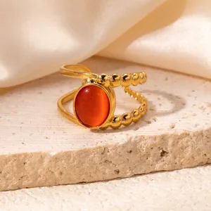 Macro detail of gold-plated double-layer ring featuring a vibrant orange oval gemstone