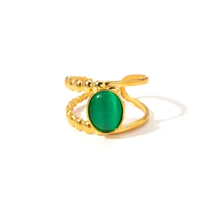 Detail of double-layered gold ring featuring a green cat-eye stone and beaded texture