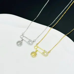 Close-up of tree of life pendants in gold and silver finish with crystal pavé on safety pins