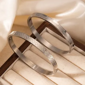 Détail de bracelets argentés texturés et lisses sur présentoir de luxe en soie