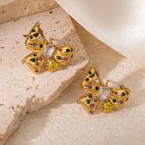 Boucles d'oreilles papillon dorées avec zircons colorés sur marbre et soie