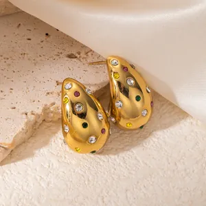 Détail macro de boucles d'oreilles en or en forme de goutte avec strass multicolores