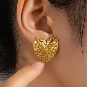 Détail de boucles d'oreilles cœur dorées avec finition texturée effet lave polie