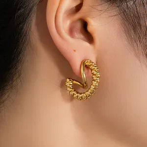 Gros plan détaillé des boucles d'oreilles dorées en C avec texture tressée sur un mannequin