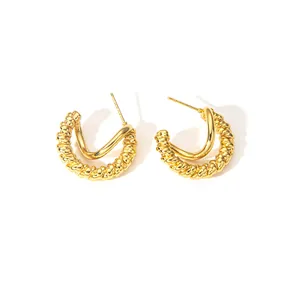 Détail de boucles d'oreilles C dorées à double couche avec textures métalliques torsadées