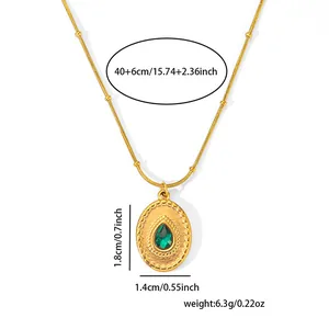 Macro shot of oval gold coin pendant with green teardrop stone and product dimensions