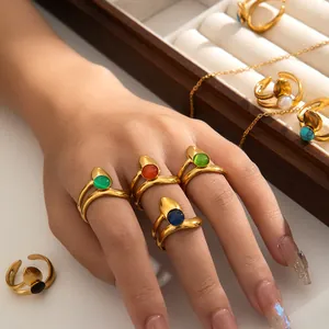 Detail of adjustable gold rings with colorful oval gemstones and double-layer wavy band
