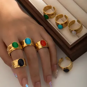 Detail van gehamerde gouden ringen met kleurrijke ovale edelstenen in houten doos