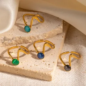 Dettaglio di anelli aperti placcati oro 18k con design a onde e pietre occhio di gatto