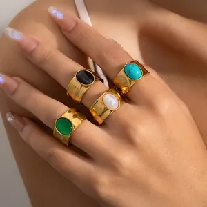 Detailweergave van brede gouden ringen met kleurrijke edelstenen en gehamerde textuur