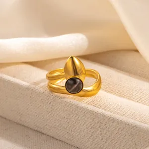 Detailed view of golden textured ring featuring a black onyx stone and water drop charm