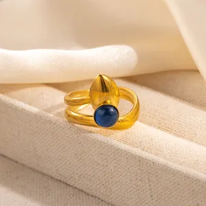 Detailed close-up of double-wrap gold ring with dark blue gemstone and drop-shaped element