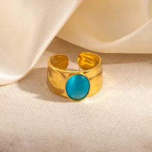 Detail van goud gehamerde ring met blauwe kattenoog edelsteen op een zijden achtergrond