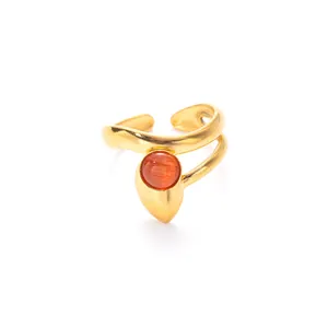Detail view of a gold-finish open ring with matte texture and an orange gemstone inlay