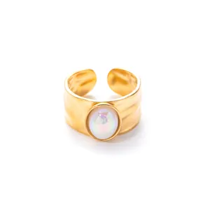 Detail van een matgouden verstelbare ring met een iriserende ovale opaal inleg
