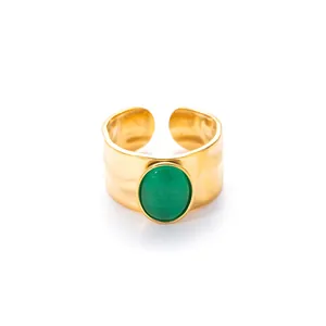 Detailopname van een brede gouden verstelbare ring met ovale groene steen en gehamerde textuur