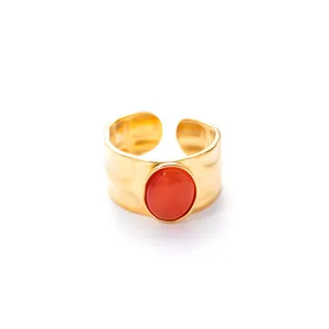 Detail van brede gouden gehamerde ring met oranje steen en verstelbare open band