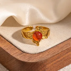 Macro di anello a farfalla retrò con gemma arancione su elegante sfondo di seta beige