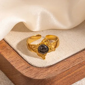 Dettaglio dell'anello regolabile dorato con pietra nera e raffinato motivo a farfalla