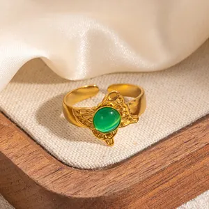 Dettaglio anello vintage placcato oro 18k con gemma verde su sfondo in seta beige