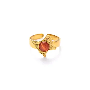 Dettaglio dell'anello regolabile dorato con farfalla traforata e occhio di gatto arancio