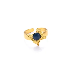Dettaglio anello regolabile dorato con una pietra blu e motivi ad ali di farfalla