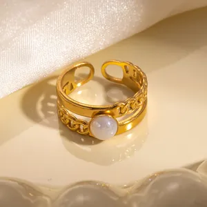 Dettaglio macro di un anello dorato a strati con trama a catena e perla bianca centrale
