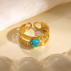 Dettaglio di un anello vintage in titanio dorato con design a catena e pietra turchese