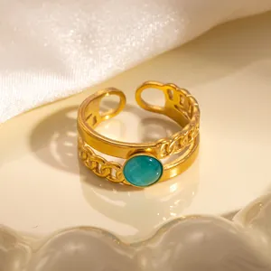 Dettaglio di un anello dorato regolabile con pietra occhio di gatto su un piatto bianco